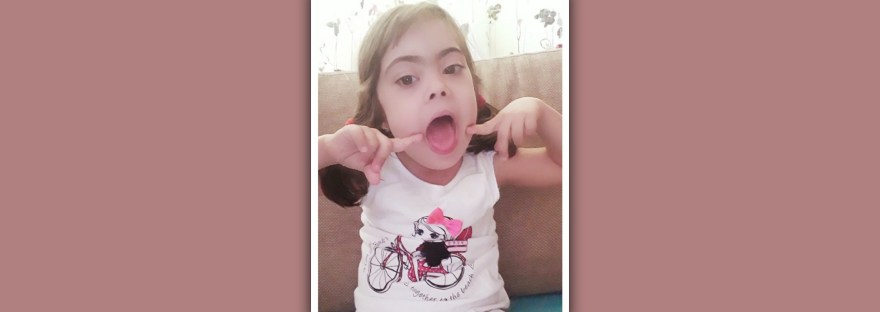 imagen nina sindrome de down señalando su boca