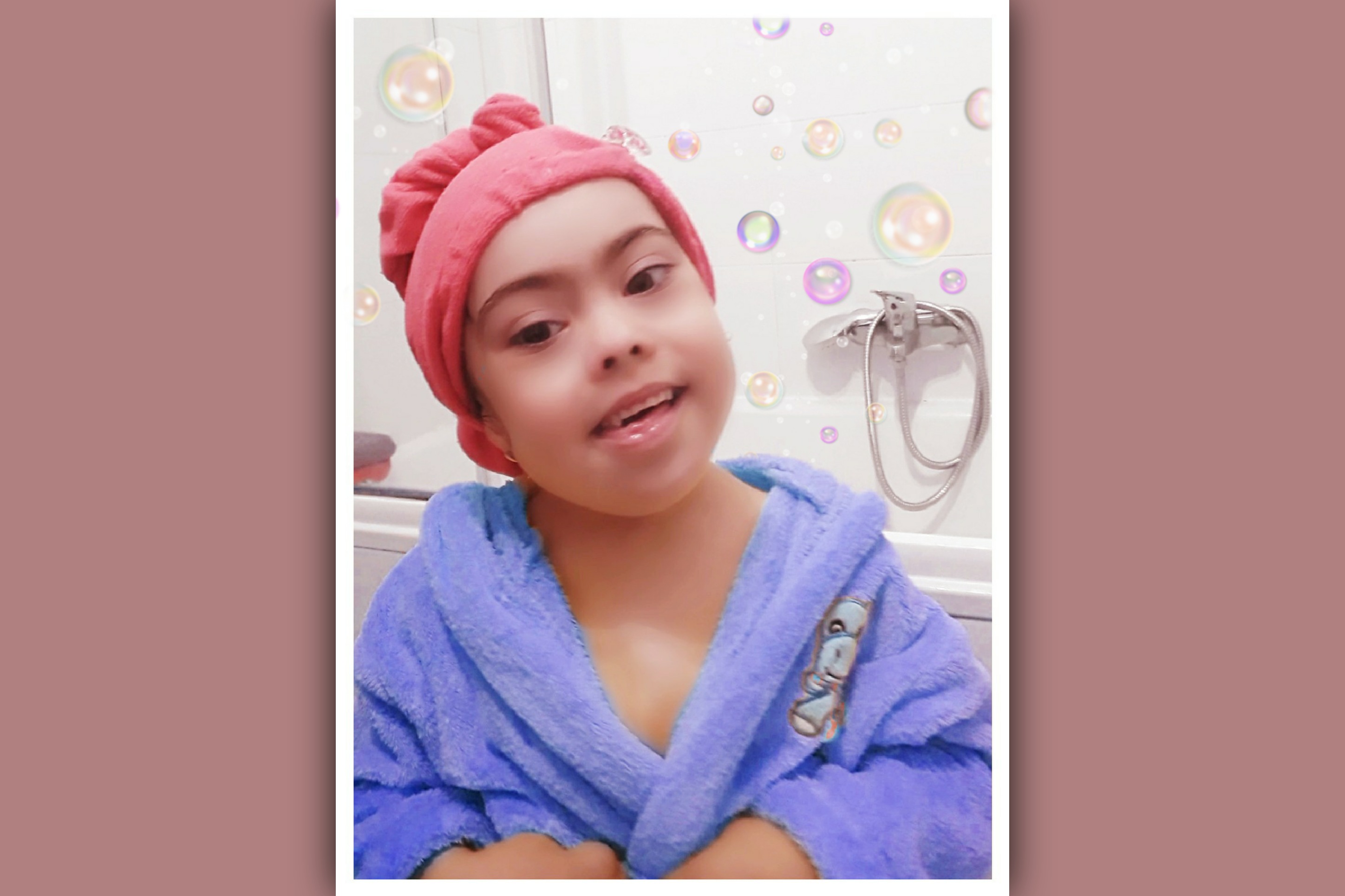 imagen de niña con sindrome de down en albornoz en su rutina de baño