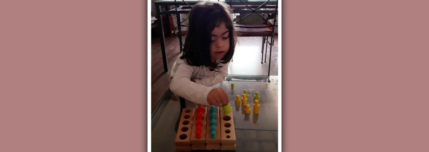 imagen niña sindrome de down con cilindros montessori
