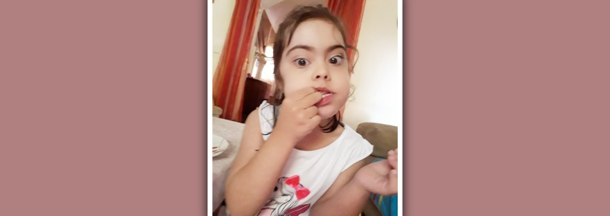 niña con sindrome de Down comiendo