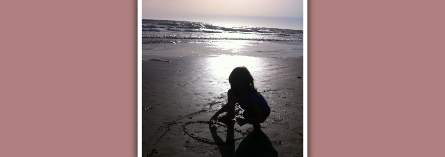 niña en la playa al atardecer dibujando un circulo en la arena