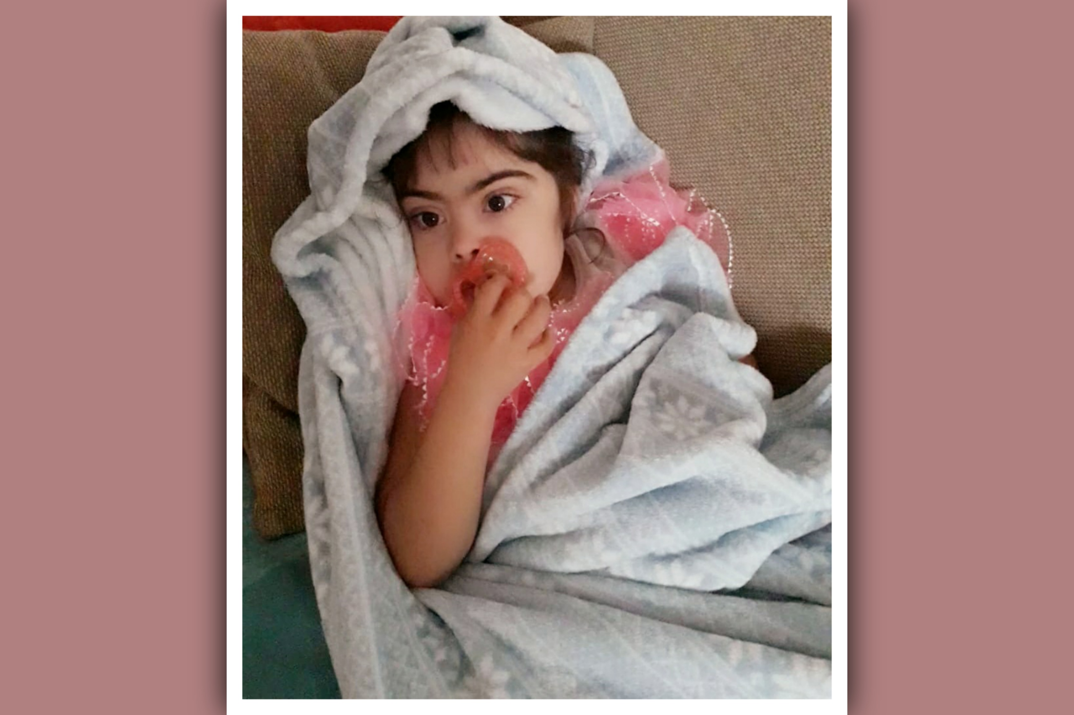 niña con síndrome de down con chupete y manta
