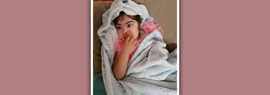 niña con sindrome de down con chupete y manta