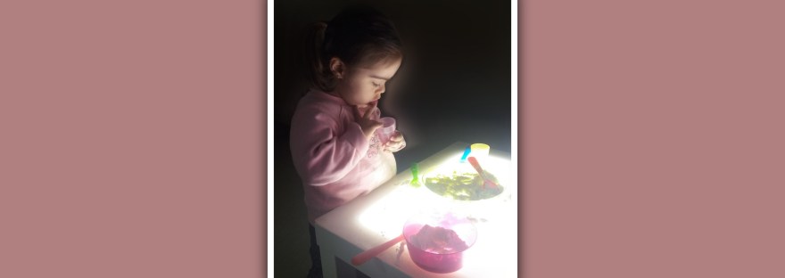 niña con sindrome de down explorando en una mesa de luz
