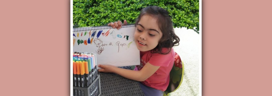 imagen nina con sindrome de down mostrando su dibujo infantil