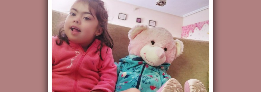 imagen niña con sindrome de down con un oso de peluche vestidos igual